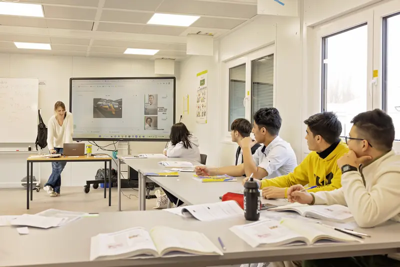 Leerlingen en leerkracht in een klaslokaal van de OKAN-school